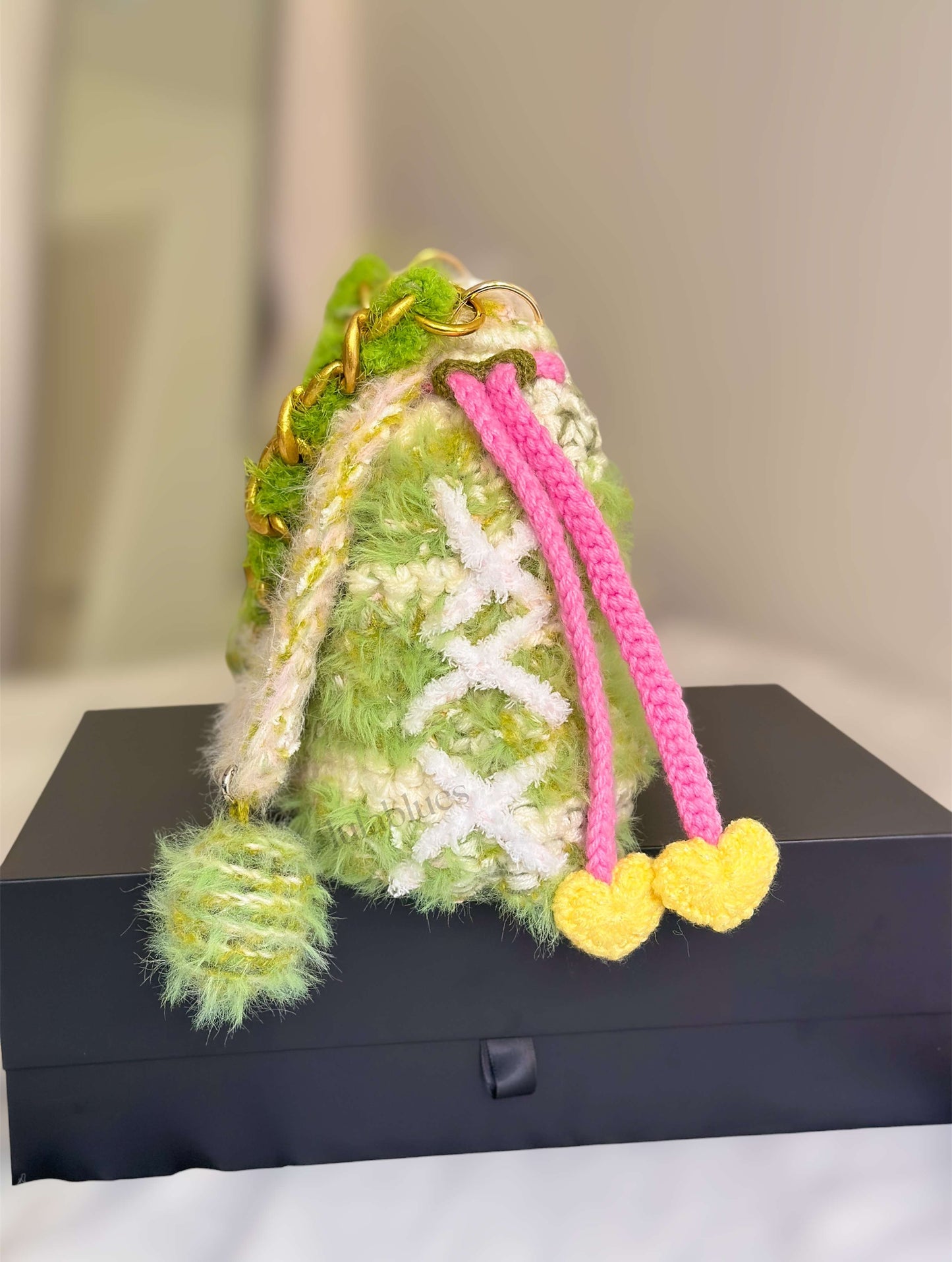 Green textured bag with pink and yellow accents on a black surface