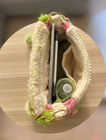 Crocheted pouch with chopsticks and a small round item on a wooden surface